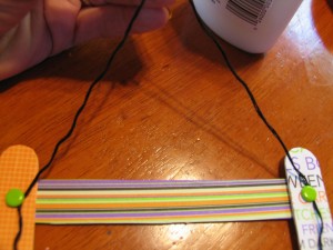 wrap other end of string around other paper fastener