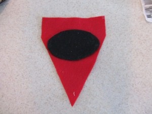 glue black oval piece onto red pennant piece