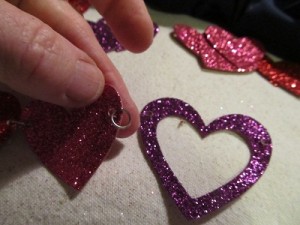 slip the o ring into the hole and then attach a heart next to it by inserting the o ring as shown